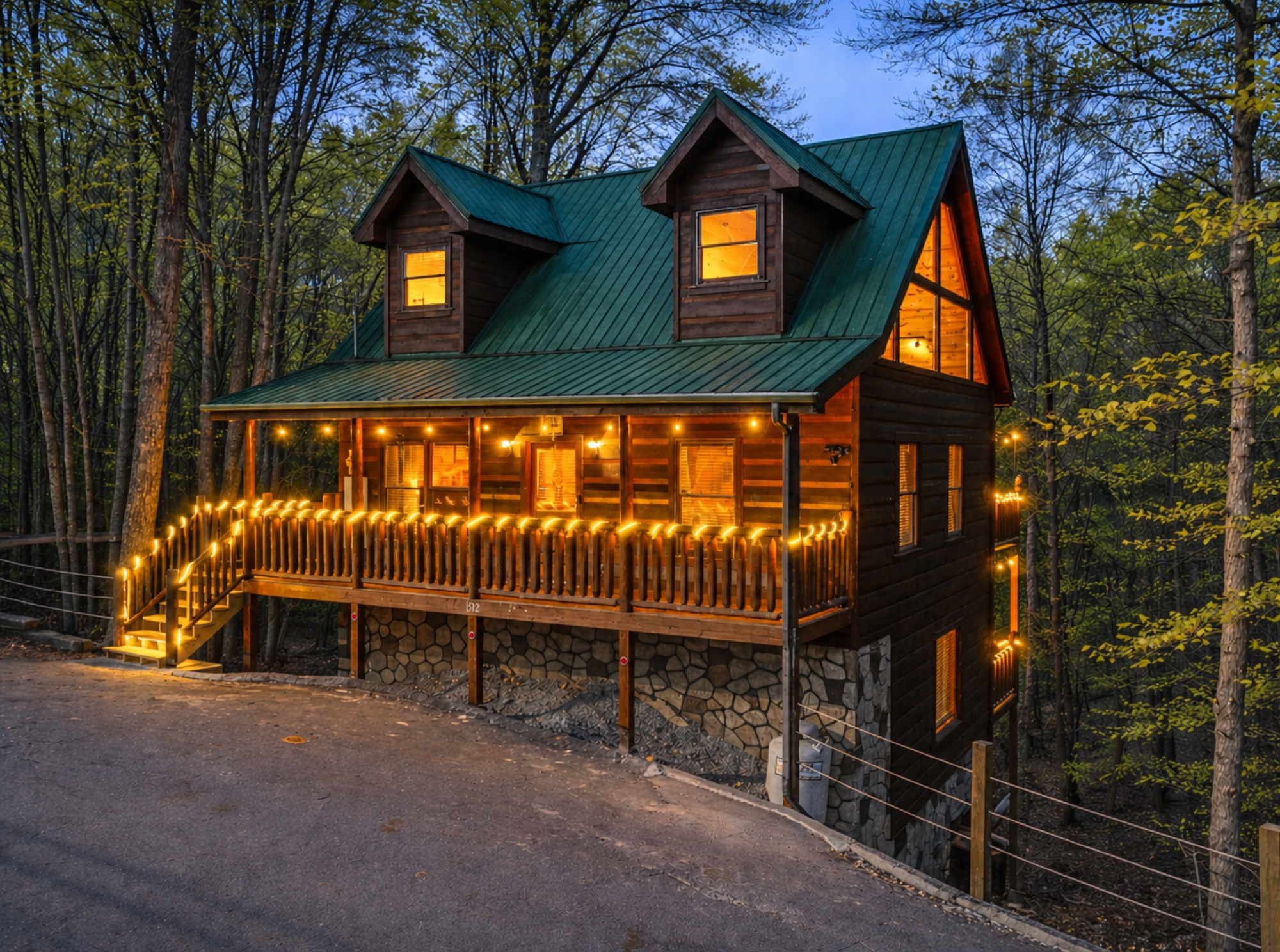 Twilight exterior of Bearadise showing its green metal roof, dormer windows, and covered porch